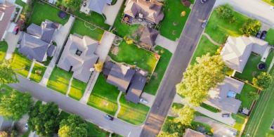 Aerial view of suburban neighborhood with houses and green lawns.