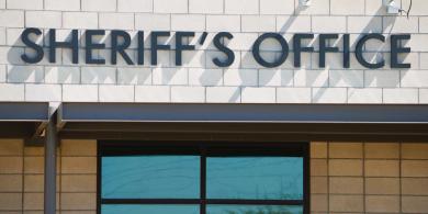 Sheriff's Office sign above a brick building window.