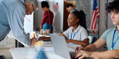 People at a voting station, registering with poll workers.
