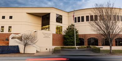 Modern building under cloudy sky during dusk, with a streaking car in front.