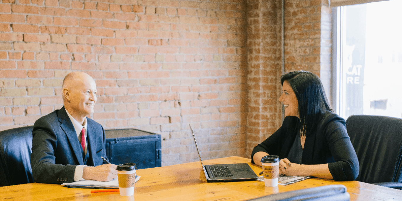 Two people sitting at a conference table, having a meeting.