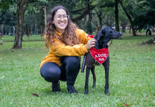 A picture of a woman with glasses putting a cloth in his dog