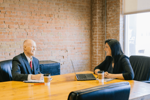 Two people sitting at a conference table, having a meeting.