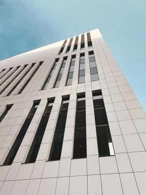 Modern white building against a blue sky, viewed from below.