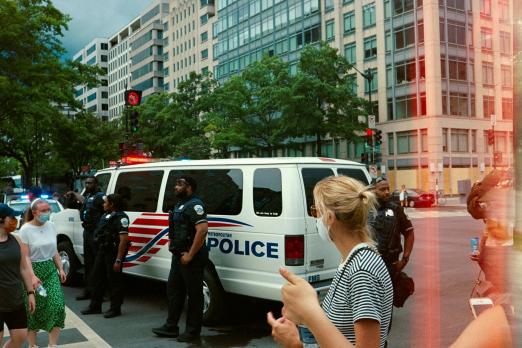 Police officers beside a van on a city street with bystanders nearby.