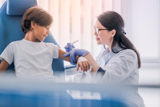 Doctor administering vaccine to smiling child in clinic.