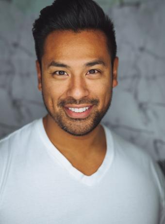 Smiling man in a white shirt with a blurred background.