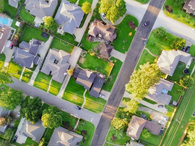 Aerial view of suburban neighborhood with houses and green lawns.